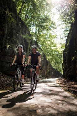 Two cyclists on a forest path with rocks