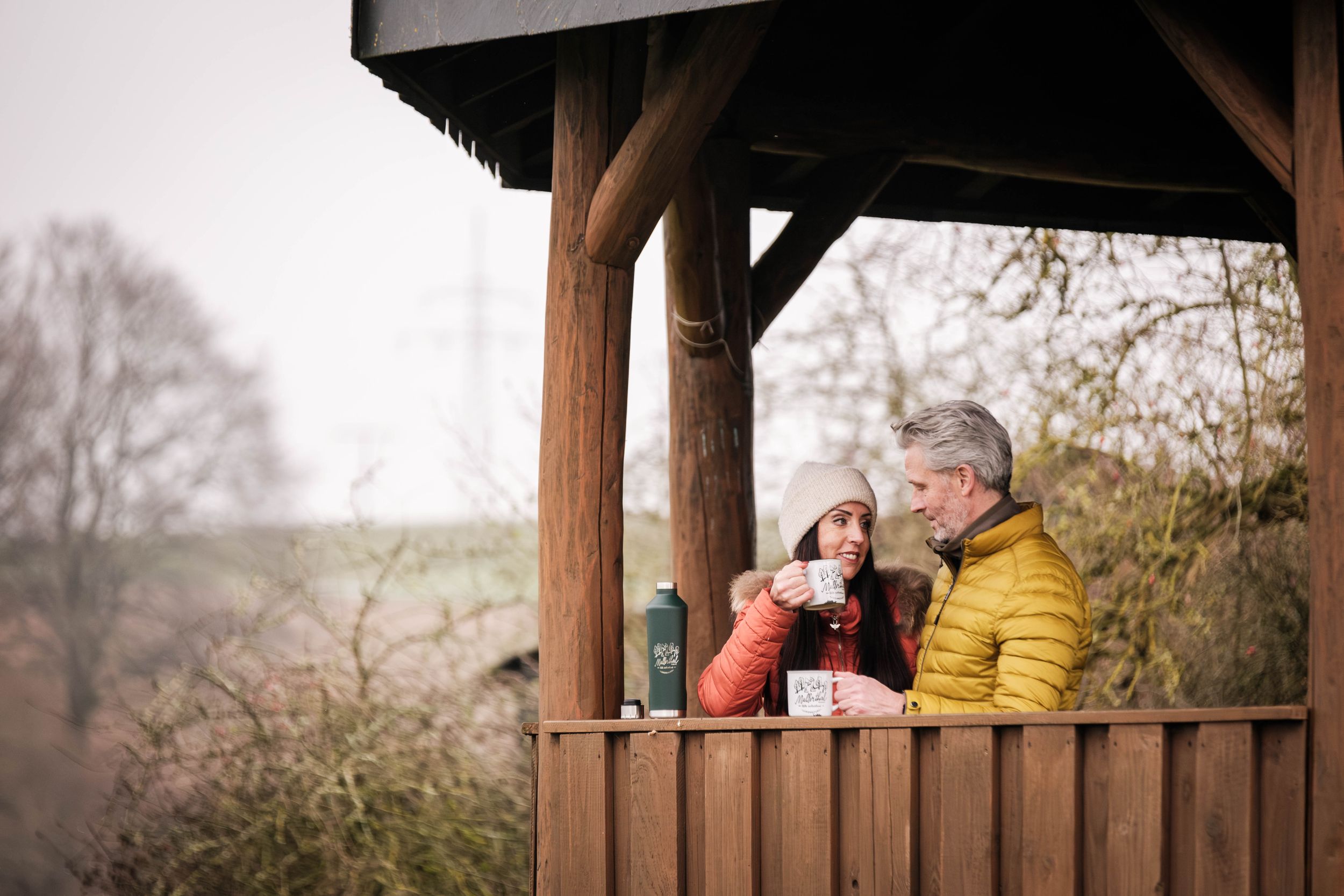 Paar trinkt zusammen eine Tasse Kaffee an einem Picknickplatz im Winter