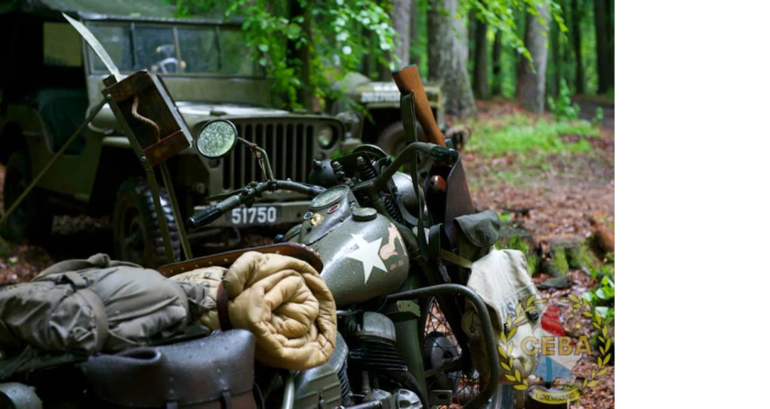 Een oude legermotor en jeep staan in het bos, omringd door bladeren en uitrusting.