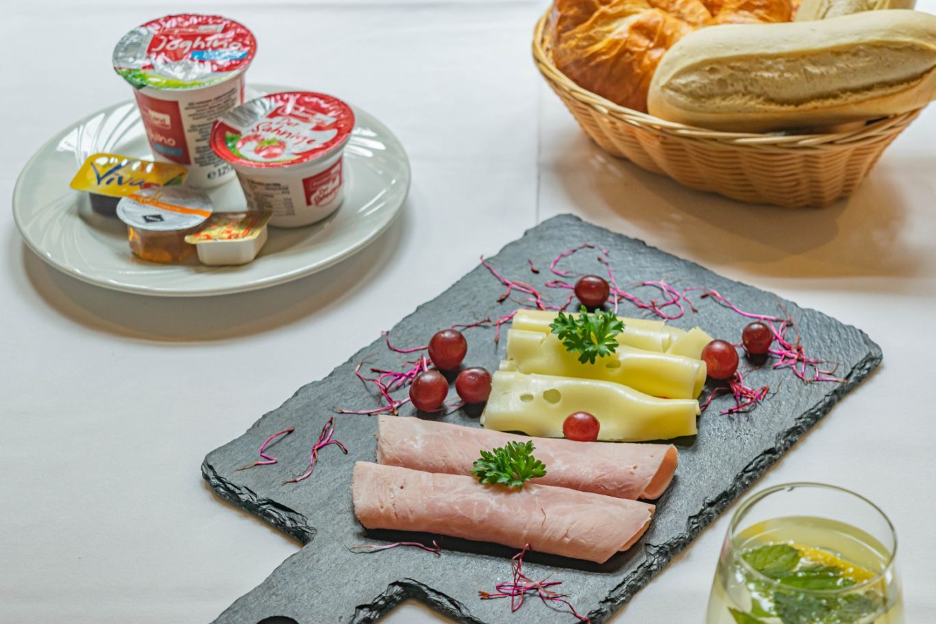 Yoghurt, broodjes, kaas en ham op de ontbijttafel