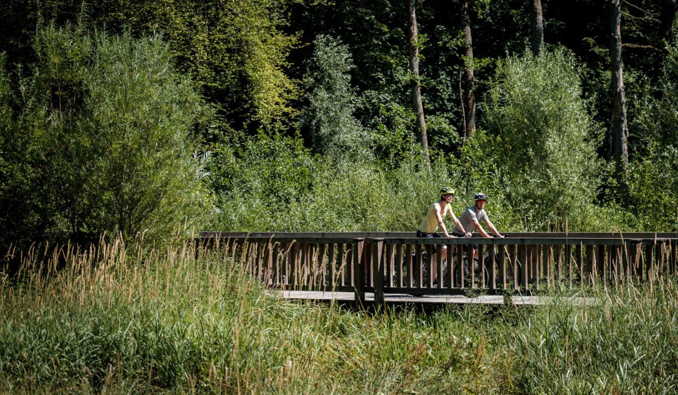 Twee fietsers op een brug langs een fietspad