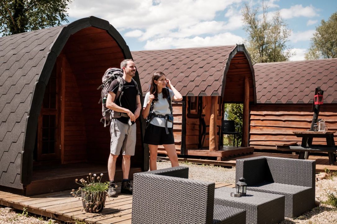 Twee personen staan voor hun campingpod, klaar voor een wandeling.