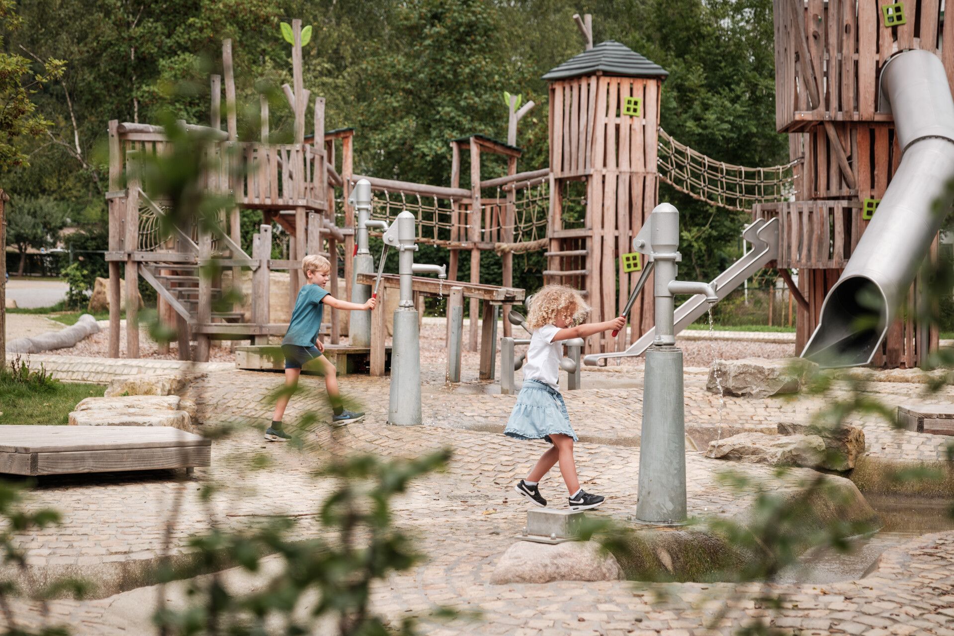 Kinderen spelen op een grote avonturenspeeltuin.